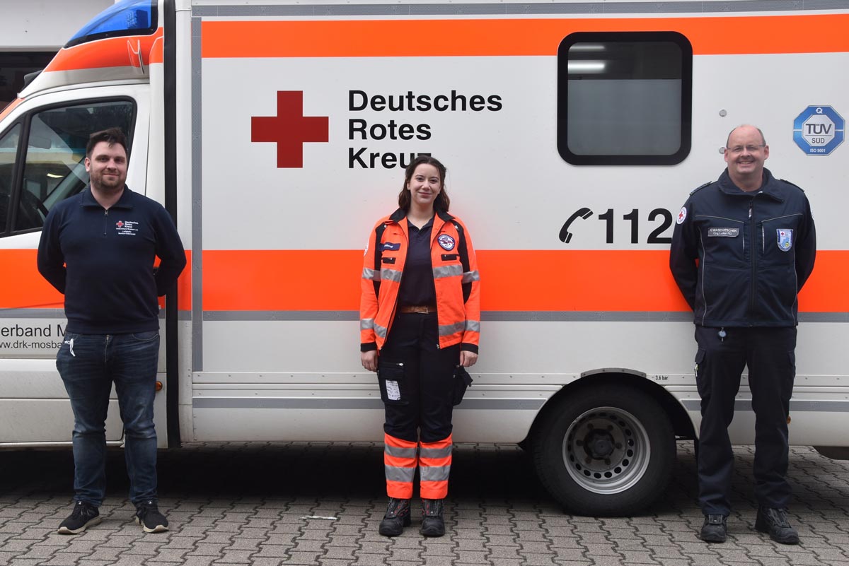 Yasmin El-Bougi (m.) mit ihren Ausbildern Robin Bracht (l.) und Henning Waschitschek (r.) vor einem Einsatzwagen an der Mosbacher DRK-Rettungswache in der Sulzbacher Straße. 