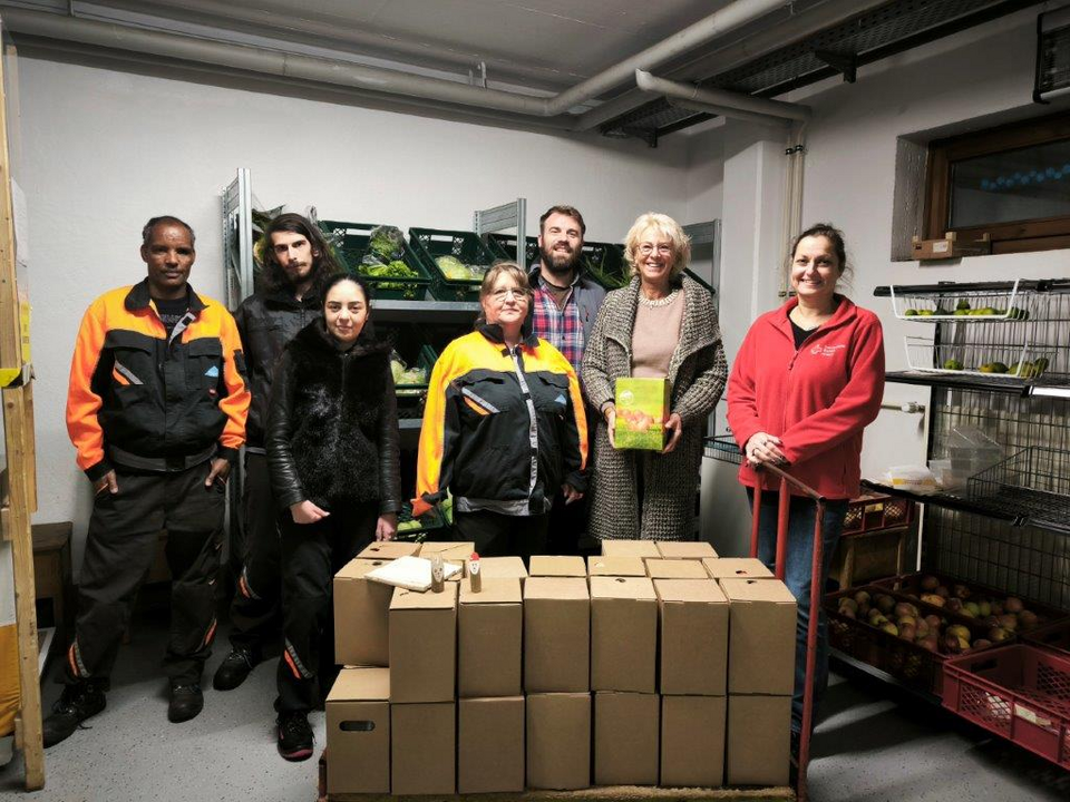 apfelsaftspende_digeno.png Personen im DRK-Tafelladen mit 40 Fünfliter-Kartons Apfelsaft