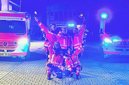 Das Bild zeigt eine Gruppe von Notfallsanitätern und zwei Rettungsfahrzeugee in der Silveternacht