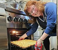 Eine Frau holt einen Kuchen aus einem Backofen