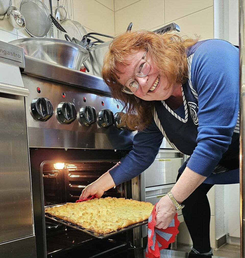 Eine Frau holt einen Kuchen aus einem Backofen