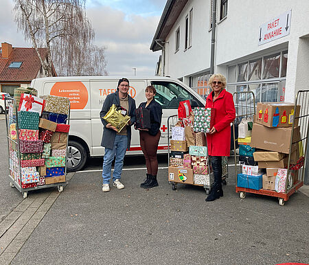 Personen vor dem Tafellladen-Fahrzeug, Paletten mit Geschenkpäckchen