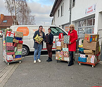 Personen vor dem Tafellladen-Fahrzeug, Paletten mit Geschenkpäckchen