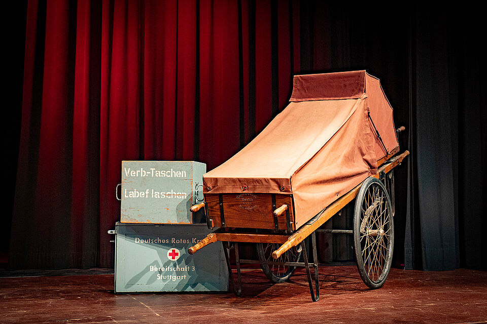 Die historische Räderfahrtrage "Marie", eine Leihgabe des Rotkreuzmuseums Geislingen, auf der Bühne. (Bild: Ben Schibor)