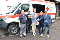 Fackelübergabe mit 5 Personen  vor Rotkreuzfahrzeug